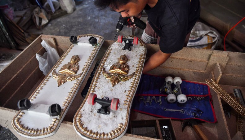 This photo taken on March 19, 2021 shows an employee from the Burapha coffin shop putting wheels on skateboards, made from wood used for coffins, in Bangkok. —AFP photo