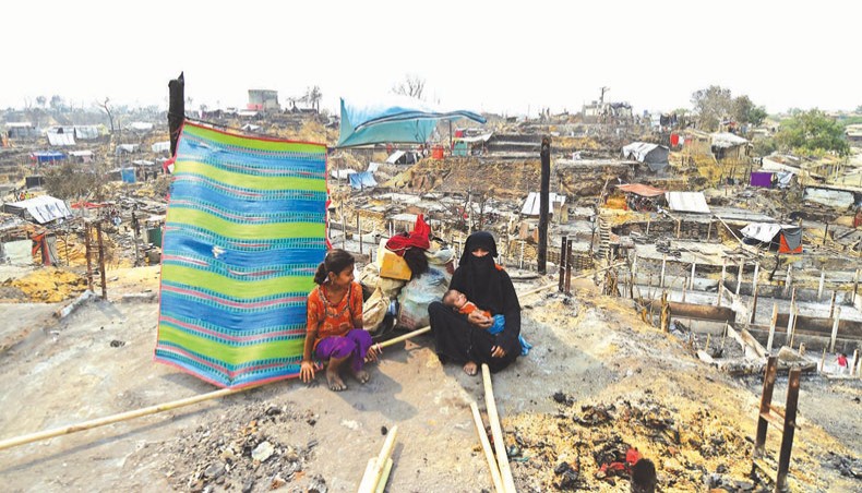 A woman sits with a child amid the temporary shelters set up for displaced Rohingyas days after a fire at a refugee camp in Ukhia of Cox’s Bazar on Wednesday in which fifteen people died and 400 residents were missing. — AFP photo