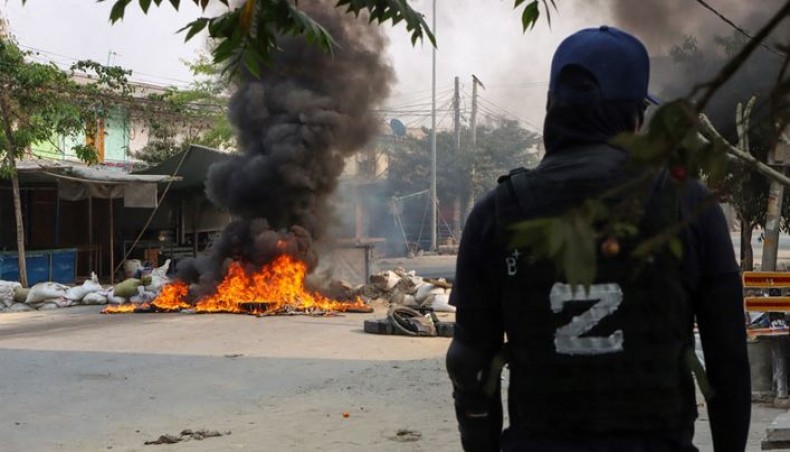 This photo taken and received courtesy of an anonymous source on March 22, 2021 shows a protester looking at a burning barricade during a crackdown by security forces on demonstrations against the military coup in Mandalay. -- AFP photo
