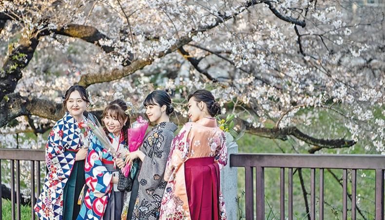 People wearing hakama, a traditional outfit for university graduation ceremonies, pose for pictures underneath cherry blossoms at Kitanomaru Park in Tokyo on March 23, 2021. — AFP photo