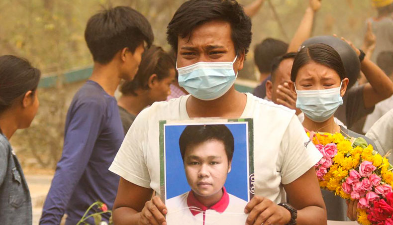 This photo taken and received from an anonymous source via Facebook on March 29, 2021 shows a relative holding the portrait of one of three protesters, who were shot dead the day before amid a crackdown by security forces on demonstrations against the military coup, during their joint funeral in Monywa, Sagaing region. — AFP photo