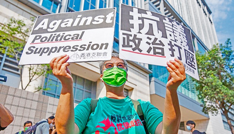A pro-democracy supporter holds signs outside West Kowloon Court in Hong Kong on Thursday, before a verdict is handed down against pro-democracy activists on charges of organising an unauthorised assembly on August 18, 2019. — AFP photo