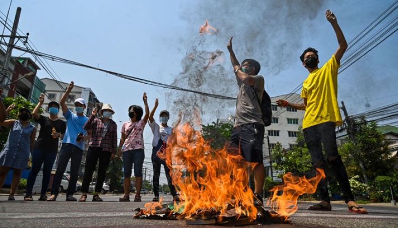 Protesters make the three-finger salute as copies of the 2008 constitution are burnt during a demonstration against the military coup in Yangon's South Okkalapa township on April 1, 2021. -- AFP photo