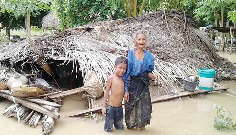 An elderly villager and her grandson stand in floodwaters in front of their damaged home in the village of Haitimuk in East Flores on Sunday, after flash floods and landslides swept eastern Indonesia and neighbouring East Timor. — AFP photo