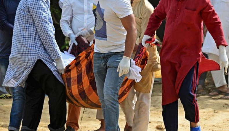 Relatives and friends carry the body of a coronavirus victim during the burial at a graveyard in New Delhi on April 5, 2021. — AFP photo
