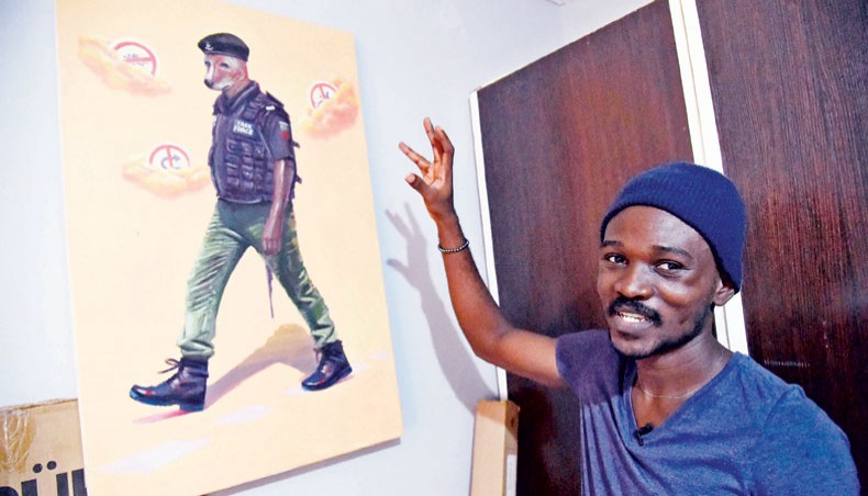 Painter Julius Agbaje points to a painting of police officer with dog head that he titled ‘Mad Dog’ at his studio residence in Ipaja, Lagos, on March 25, 2021. — AFP photo