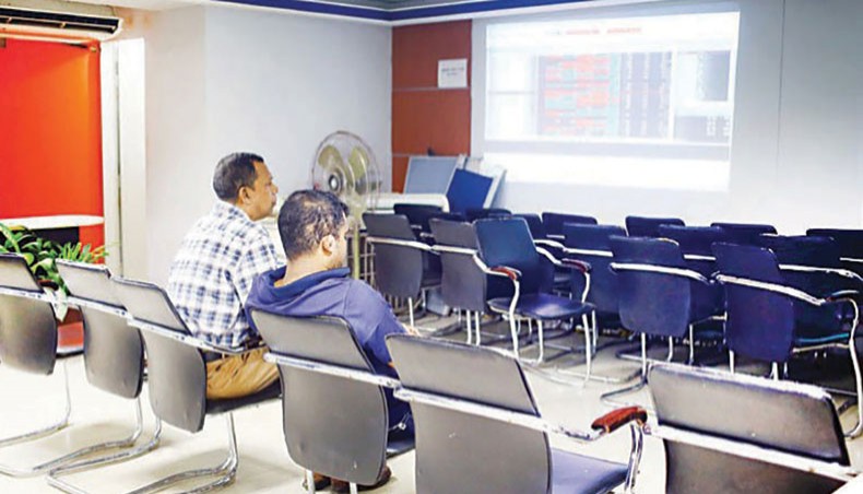 A file photo shows investors looking at share price movements on a computer screen at a brokerage house in the capital. Dhaka stocks dipped in the past week, stretching the losing streak to the fourth week as investors continued selling shares amid an alarming deterioration in the COVID-19 outbreak situation in the country.— New Age photo