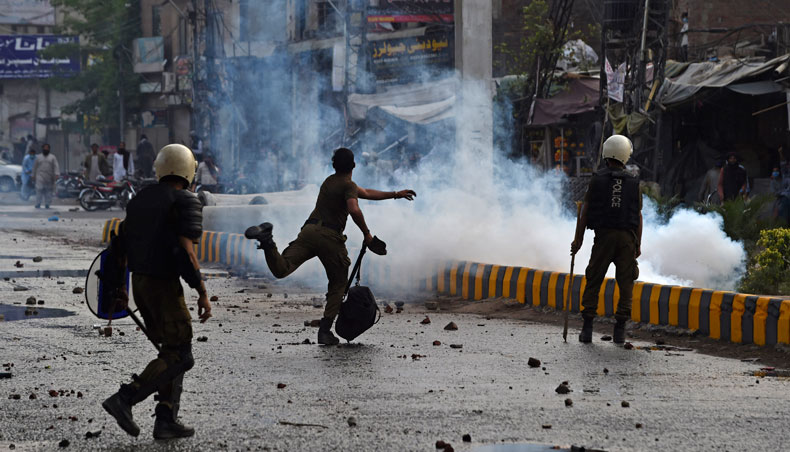 A policeman throws a stone towards supporters of Tehreek-e-Labbaik Pakistan during a protest in Lahore on April 12, 2021, after the arrest of their leader, who has called for the expulsion of the French ambassador. — AFP photo