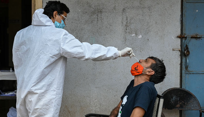 A health worker takes a nasal swab sample of a resident for a COVID-19 test at a medical centre in Dharavi slums in Mumbai on April 17, 2021. — AFP photo