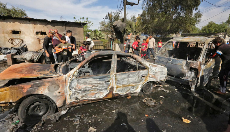 People gather around destroyed vehicles at the scene of an explosion in the Habibiya district of the Sadr City suburb of Iraq’s capital Baghdad on April 15, 2021. — AFP photo