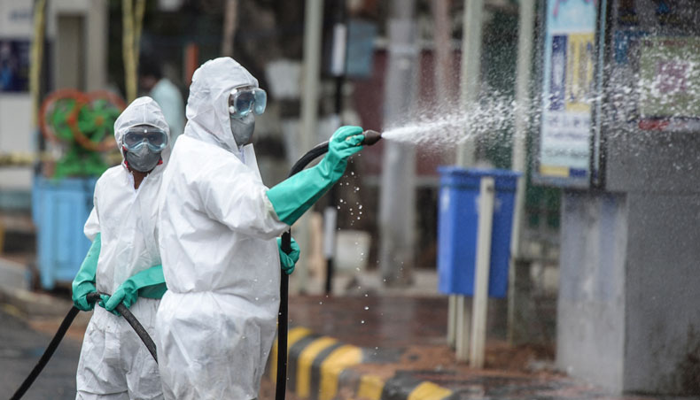 Members from the Disaster Response Force of Telangana State, wearing protective gear spray disinfectant on a street against the spread of COVID-19 in Hyderabad on April 19, 2021. — AFP photo