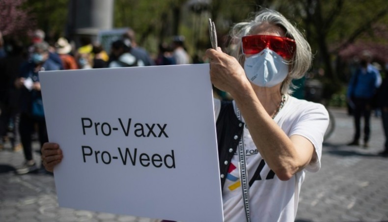 A woman holds up a sign and joints as marijuana activists hand out free joints to vaccinated New Yorkers on April 20, 2021. -- AFP photo