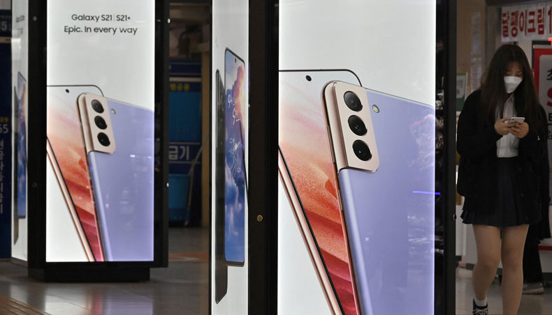 This picture taken on April 28, 2021 shows a woman walking past an advertisement for the Samsung Galaxy S21 smartphone at an underground shopping area in Seoul. — AFP photo