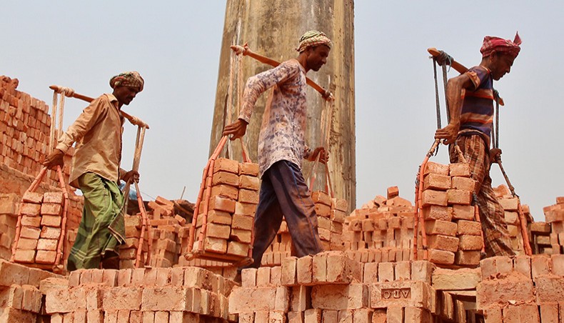 Workers without safety gears carry bricks on shoulders at a brick kiln at Amin Bazar in Dhaka on Friday. — Sony Ramany