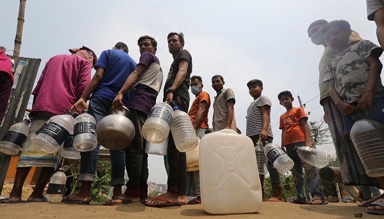 People collect water from a roadside source at Kajla in Jatrabari of the capital city on Monday without maintaining the Covid health guidelines. — Sourav Lasker
