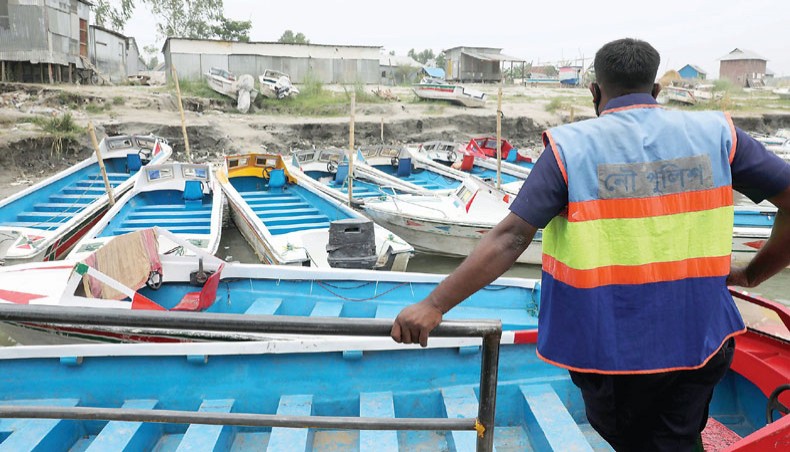 A river police officer stands guard to prevent speedboats from running on the River Padma at Mawa speedboat terminal in Munshiganj on Tuesday following a deadly accident involving a speedboat on the previous day. — Sony Ramany