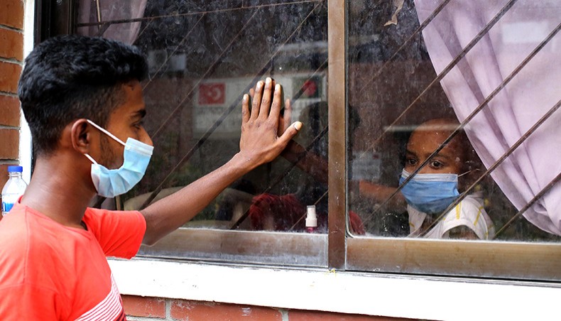 A relative of seven-year-old Atikul, who is undergoing cancer and Covid treatment at an isolation ward of Dhaka Shishu Hospital, communicates with him through a window standing outside the hospital on Sunday. — Sourav Lasker