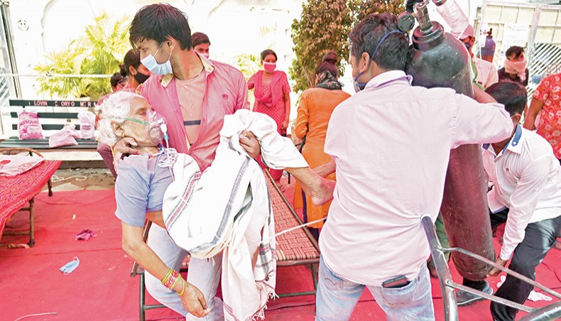 A family member carries a patient breathing with the help of oxygen being provided by a Gurdwara, a place of worship for Sikhs, under a tent installed along the roadside amid Covid-19 coronavirus pandemic in Ghaziabad on Tuesday. — AFP photo