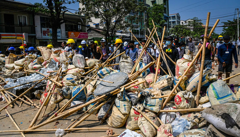 In this file photo taken on March 19, 2021, protesters take cover behind makeshift barricades during a demonstration against the military coup in Yangon’s Thaketa township. — AFP photo