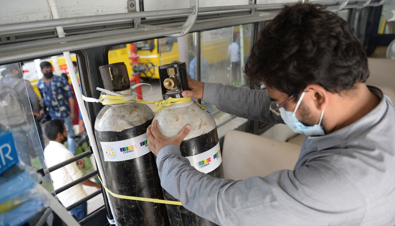 A volunteer arranges oxygen cylinders inside a bus converted to provide oxygen to Covid-19 patient with breathing problems while waiting to be admitted at government hospital on May 5, 2021. — AFP photo