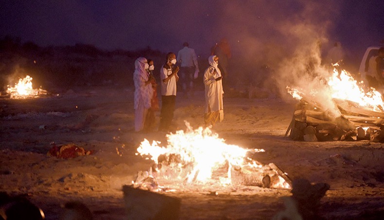 Relatives stand near the funeral pyre of their loved one who died due to the Covid-19 coronavirus at a cremation ground in Allahabad on Thursday. — AFP photo