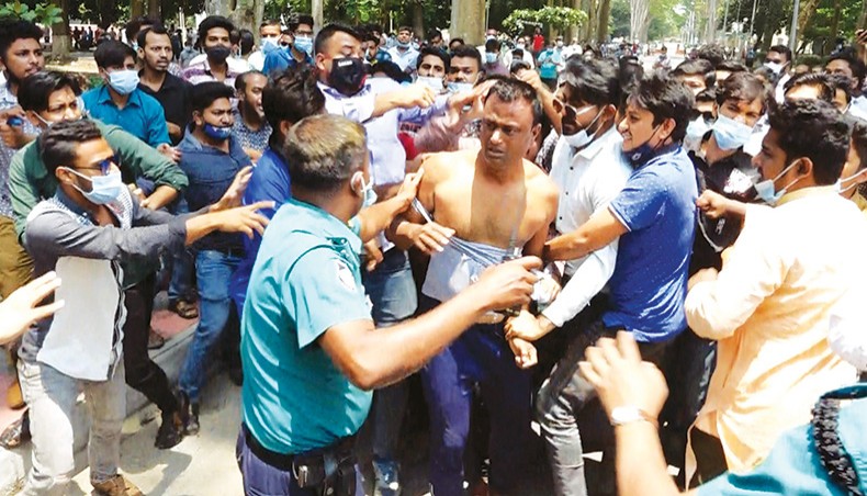 A police officer tries to restrain Bangladesh Chhatra League activists during a clash between the organisation’s Rajshahi University branch and city branch activists on the campus on Thursday. — Star Mail photo