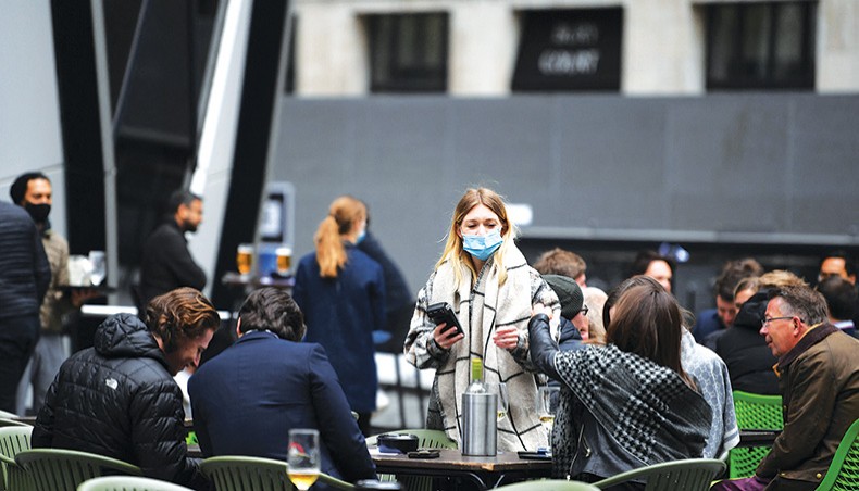 A file photo shows a worker taking customers’ orders as they sit at tables outside a bar in the City of London on April 29, 2021. The Bank of England said on Thursday that the UK economy would enjoy a stronger than expected recovery this year as the country eases its coronavirus pandemic lockdowns quicker than earlier anticipated. — AFP photo