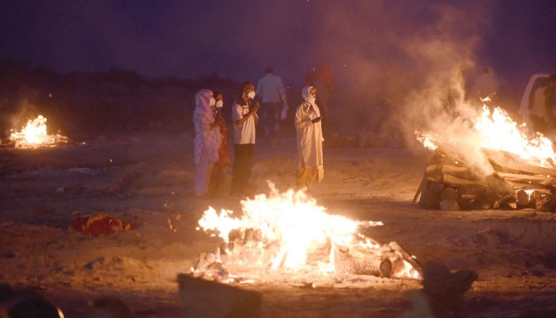 Relatives stand near the funeral pyre of their loved one who died due to the Covid-19 coronavirus at a cremation ground in Allahabad on Thursday. — AFP photo