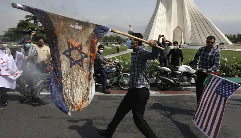 Demonstrators burn representations of Israeli and US flags during the annual Al-Quds, or Jerusalem, Day rally, with the Azadi monument tower seen at right, in Tehran, Iran, on Friday. — AP photo/ UNB
