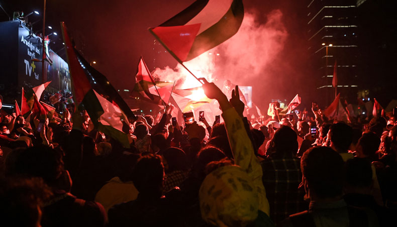 Smoke rises from a flare as people wave Palestinian flags during a protest against Israel in front of the Israeli Consulate in Istanbul, late on May 10, 2021. — AFP photo