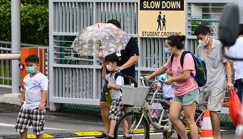 Children walk home with their guardians after school in Singapore on May 17, 2021, as the country prepares to shut all schools and switch to home-based learning until the end of the term due to a rise in the number of Covid-19 cases. — AFP photo