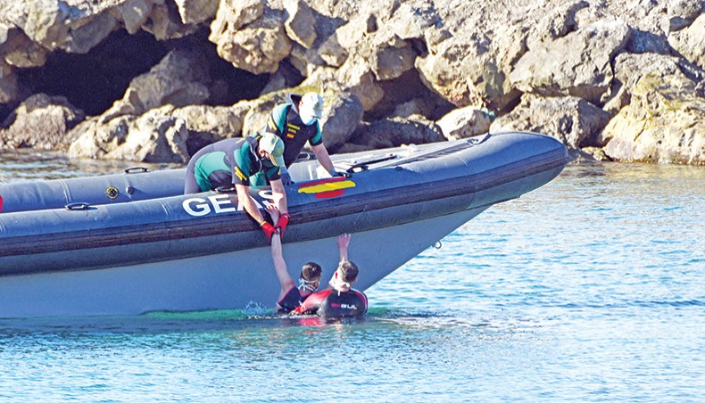 Spanish Civil guards pull a migrant into an inflatable boat after he arrived swimming to the Spanish enclave of Ceuta from neighbouring Morocco on Monday. — AFP photo