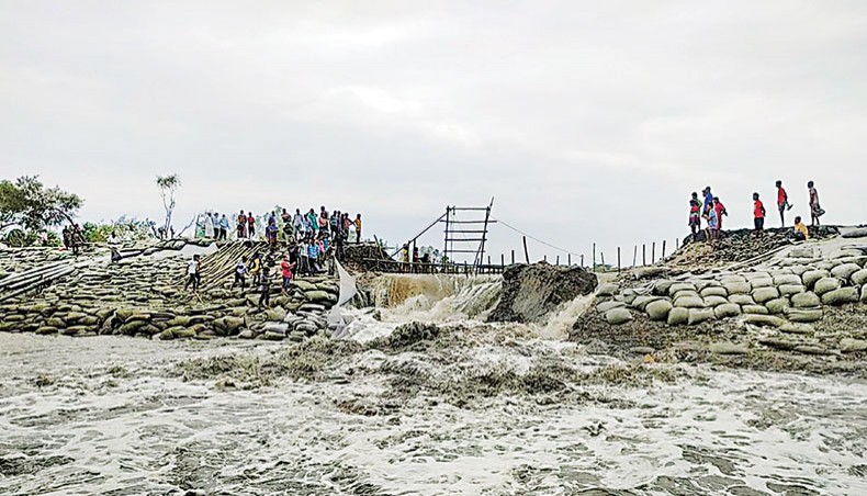 Local people try to stop the Kobodak River water gushing through an embankment damaged by the super cyclone Amphan, inundating the cropland of Gabura area in Shyamnagar upazila of Satkhira district recently. — New Age photo