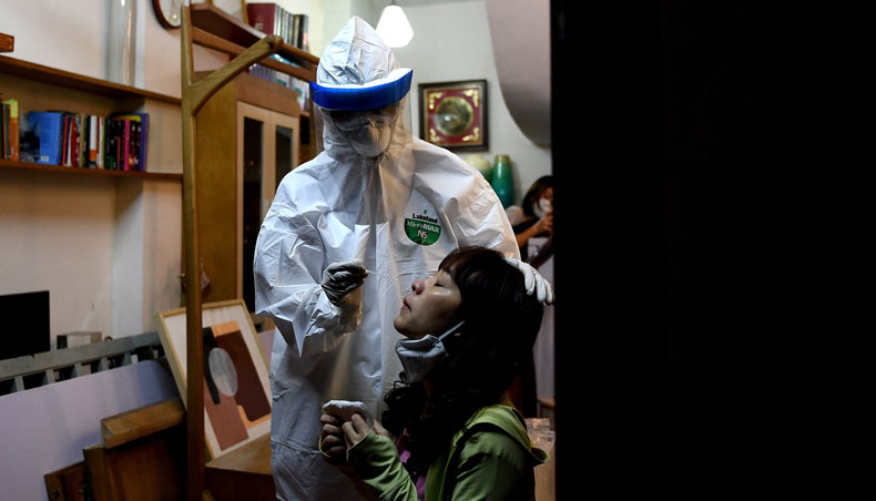 In this file photo taken on March 30, 2020, a health worker, wearing protective clothing amid concerns of the spread of Covid-19, conducts a swab test on a woman in her house in Hanoi. — AFP photo