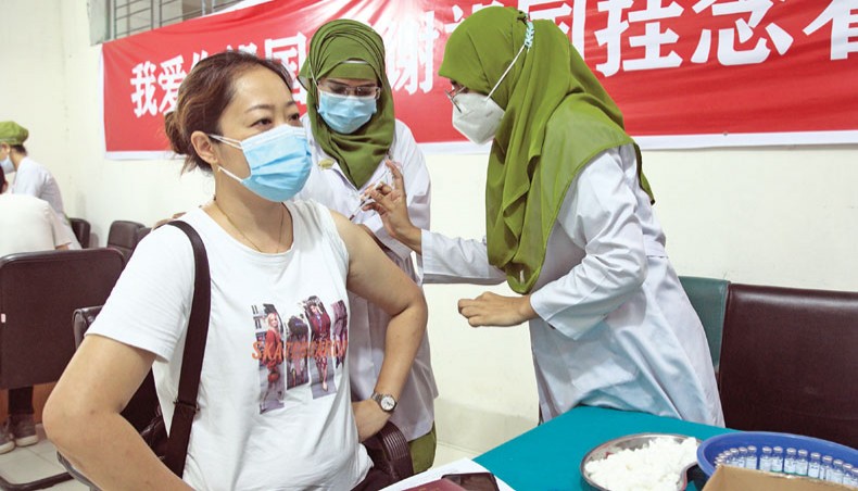 Health workers inoculate a Chinese citizen with Covid vaccine donated by the Chinese government at Dhaka Medical College Hospital on Saturday. — New Age photo
