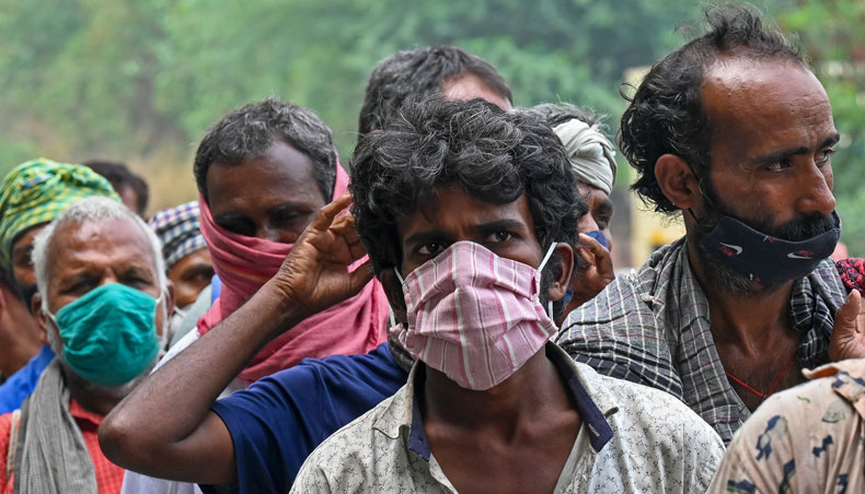 Homeless people mostly working as daily wage labourers and are out of jobs due to the lockdown imposed to curb the spread of Covid-19, queue up as volunteers distribute food along the roadside in New Delhi on May 20, 2021. — AFP photo