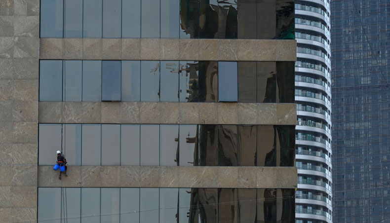 A worker cleans glass windows of a building in Mumbai on June 4, 2021. — AFP photo