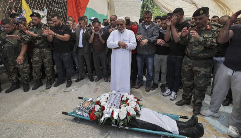 Mourners pray by the body of Adham Eleiwi, a Palestinian military intelligence agent who was killed in a confrontation with Israeli special forces, during his funeral in the village of Zawata, west of Nablus in the occupied West Bank on June 10, 2021. Three Palestinians were killed early on June 10 by special Israeli forces who were on an arrest mission in the northern West Bank, sources on both sides said. One of the Palestinians killed was suspected of having carried out a shooting attack against Israeli soldiers, an Israeli security official said. The other two were members of the Palestinian Authority security forces who witnessed the initial exchange of fire. --- AFP photo