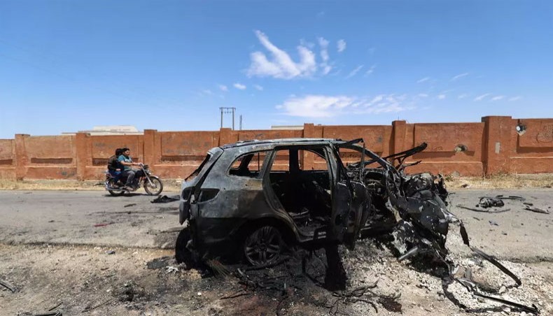 Syrians on a motorbike drive past the carcass of a charred car, hit in reported bombardment by government forces on the village of Iblin in the Jabal al-Zawiya region in Syria's rebel-held northwestern Idlib province on June 10, 2021. -- AFP photo