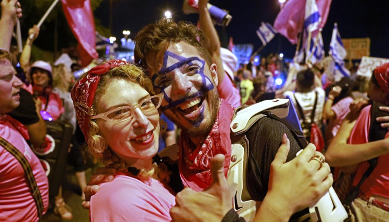 Israeli demonstrators celebrate the passing of a vote confirming a new coalition government during a rally in front of the Knesset during a parliamentary vote, in Jerusalem on Sunday. —AFP photo